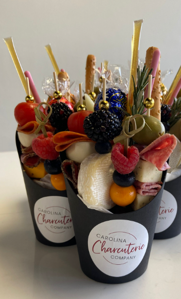 Elegant closeup of individual charcuterie cups with skewers, berries, and cheese