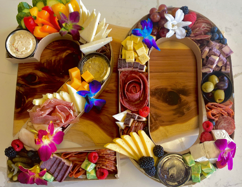 Custom number-shaped charcuterie display featuring cheeses, meats, vegetables, olives, and fruit.