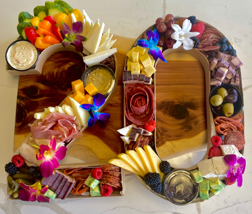 Custom number-shaped charcuterie display featuring cheeses, meats, vegetables, olives, and fruit.