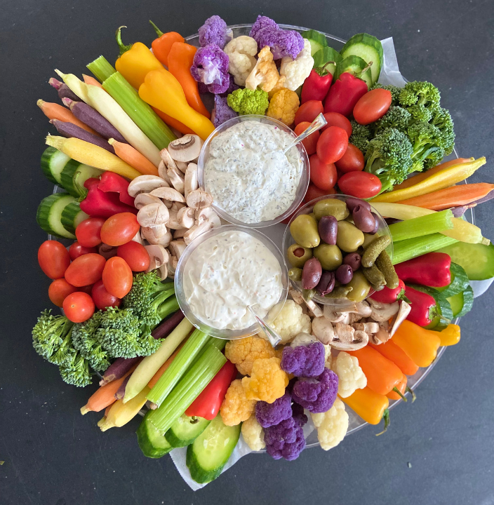 Crudité board with fresh vegetables, dipping sauces, and olives